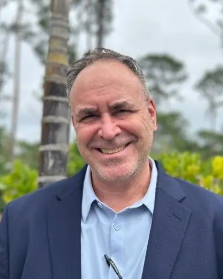 Bruno Pouliot smiling outdoors in a navy blazer and light blue shirt